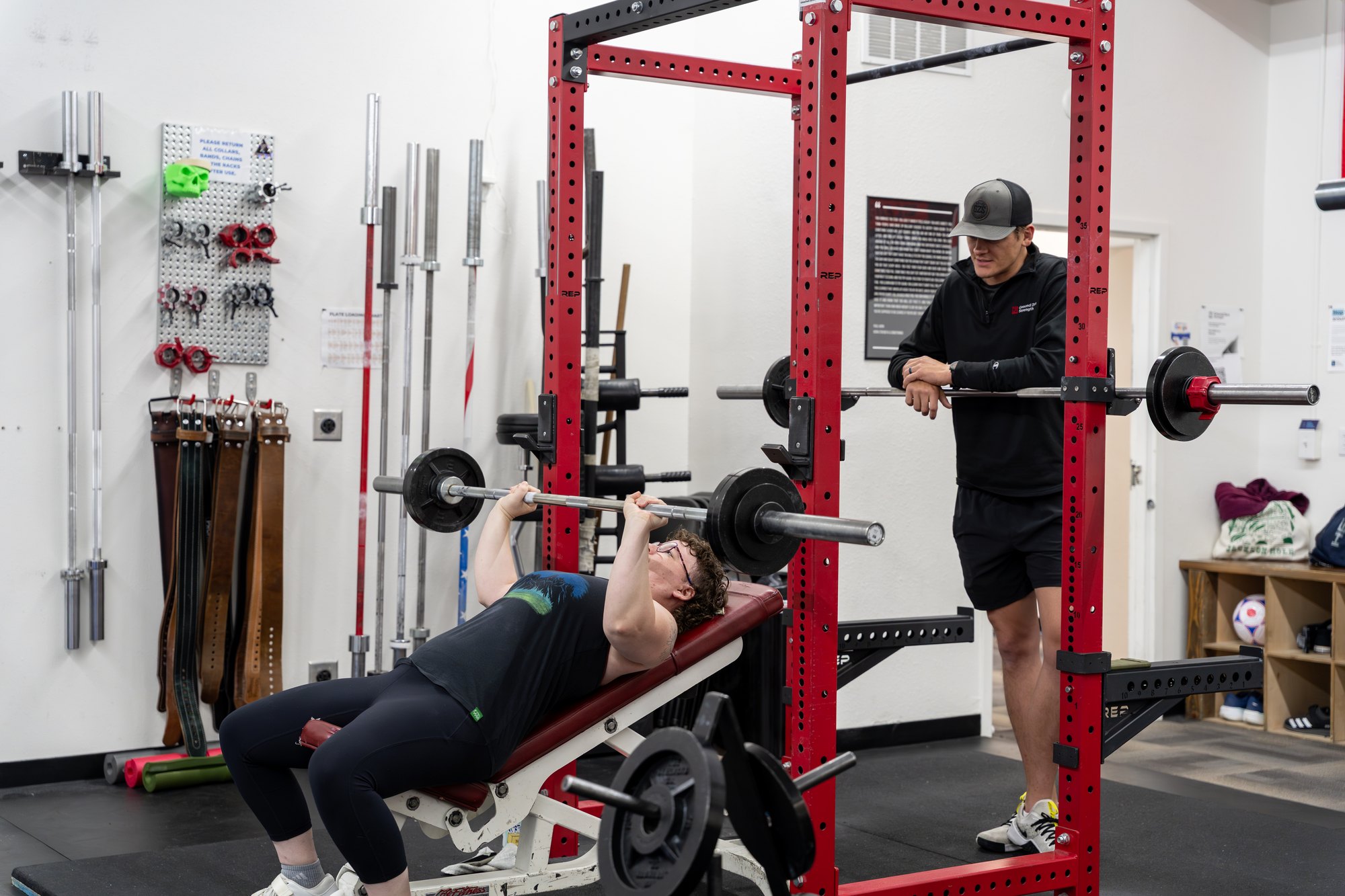 A Ground Zero Strength coach watching closely as a member bench presses