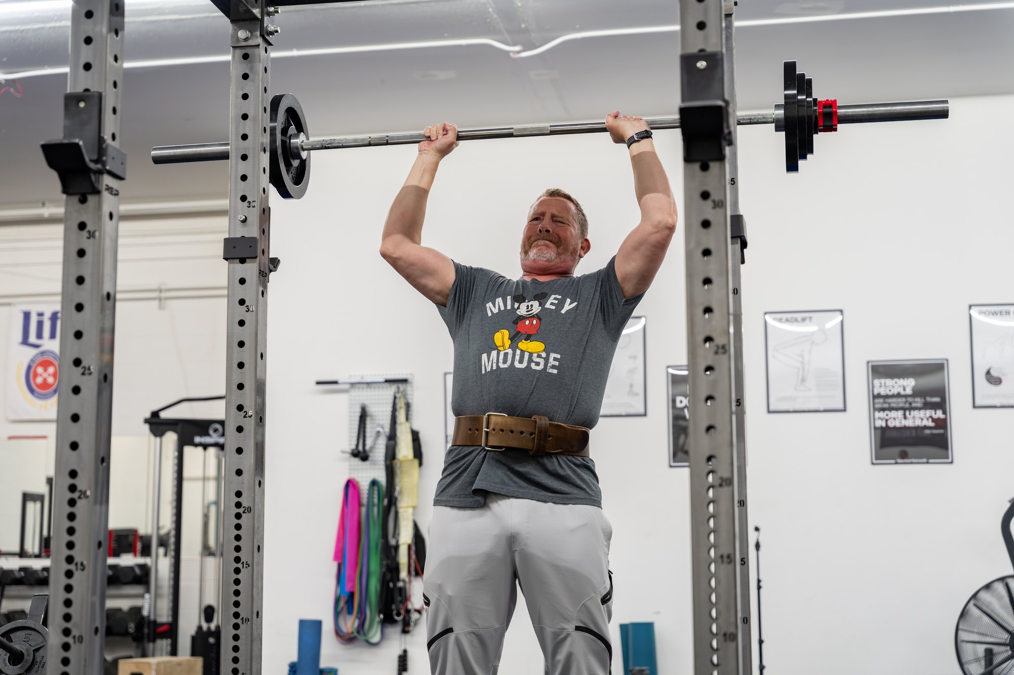 An adult pressing a barbell overhead with good technique