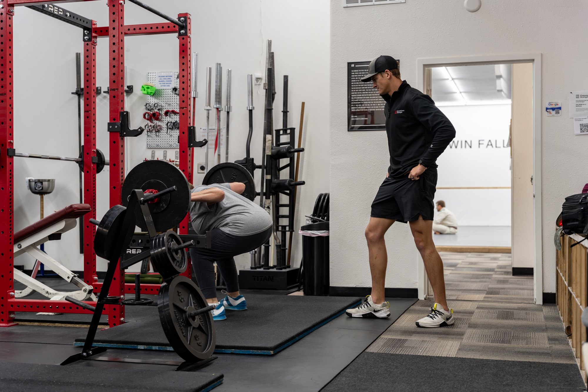 A Starting Strength coach working with a lifter at Ground Zero Strength