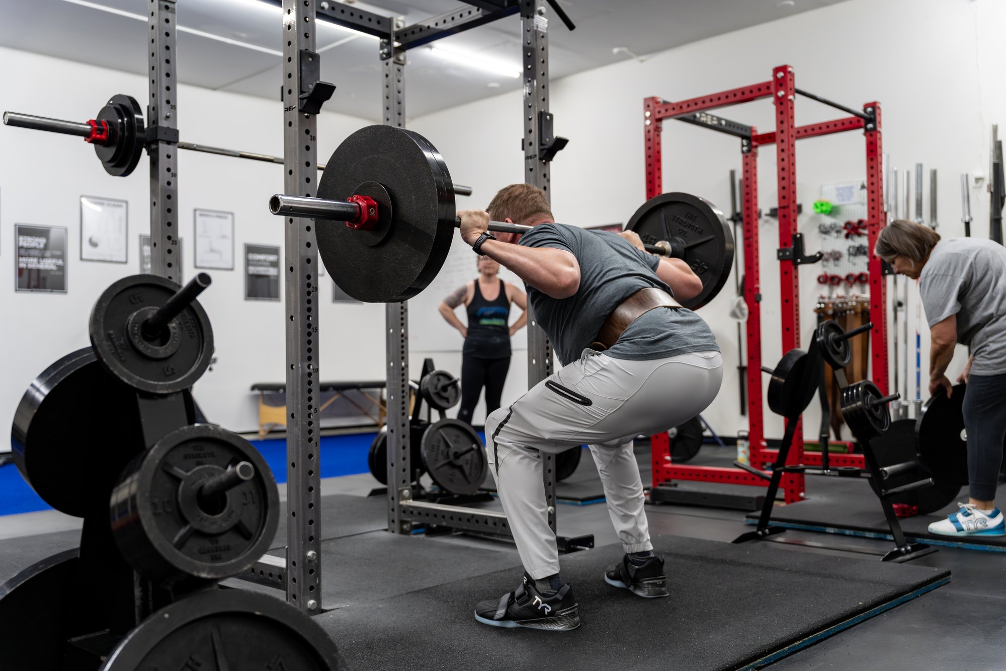 An adult performing a barbell back squat in the rack