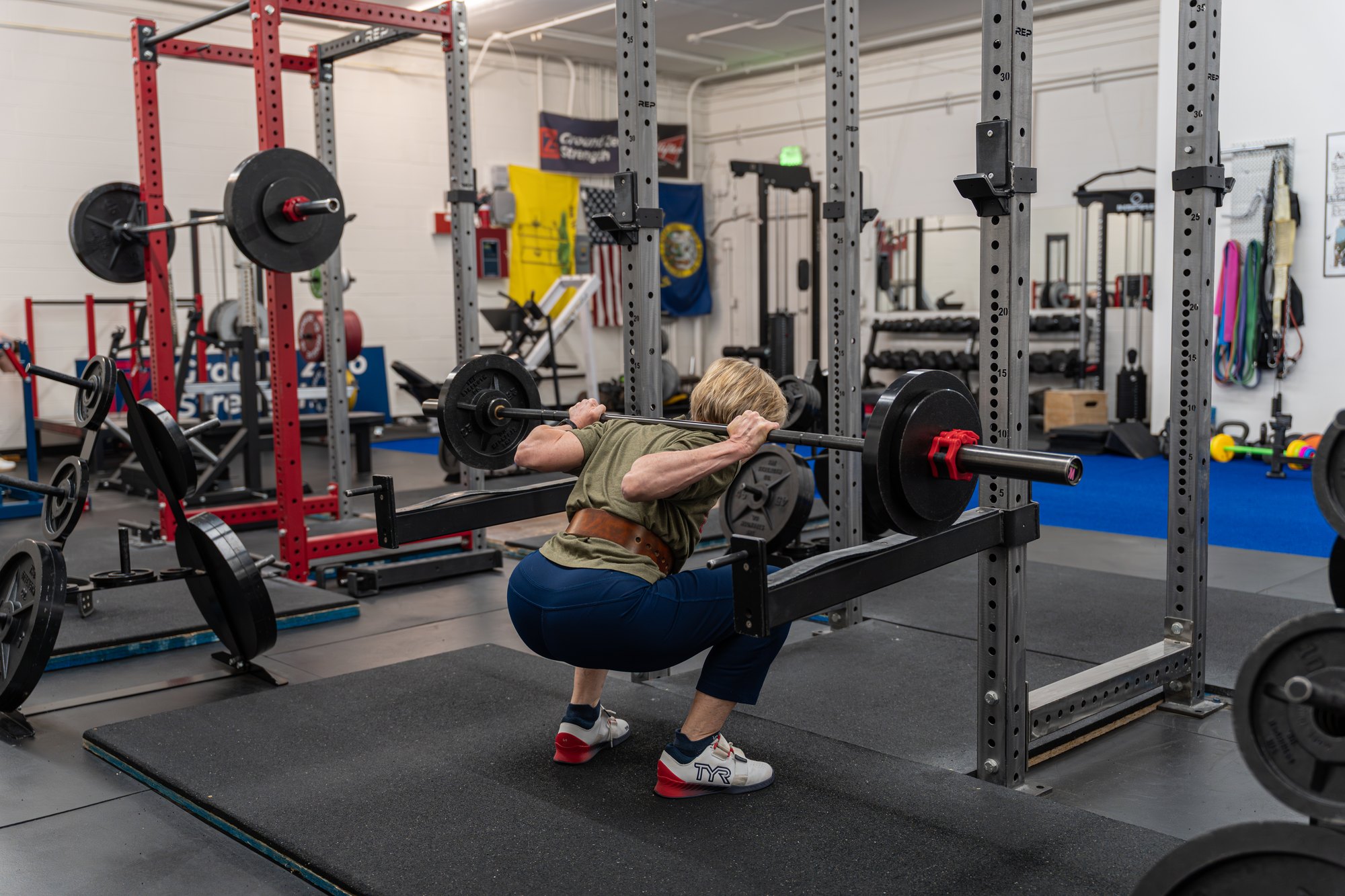 A woman performing a barbell back squat at Ground Zero Strength